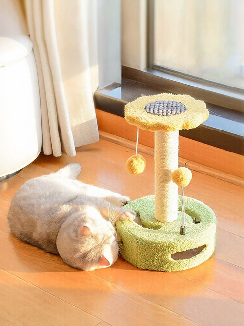 Little Pets Club Bloom Cat Scratcher with yellow pom balls and a plush green base. A light-colored cat rests beside it.
