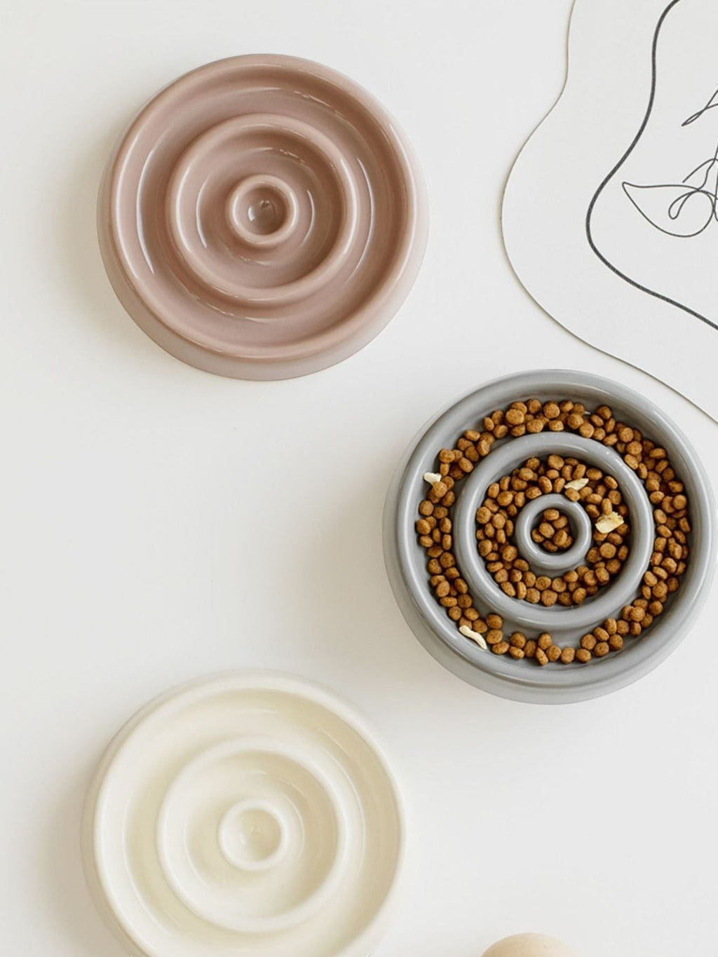 Little Pets Club taupe, grey, and cream ceramic slow feeder bowls with spiral patterns for cats and dogs.