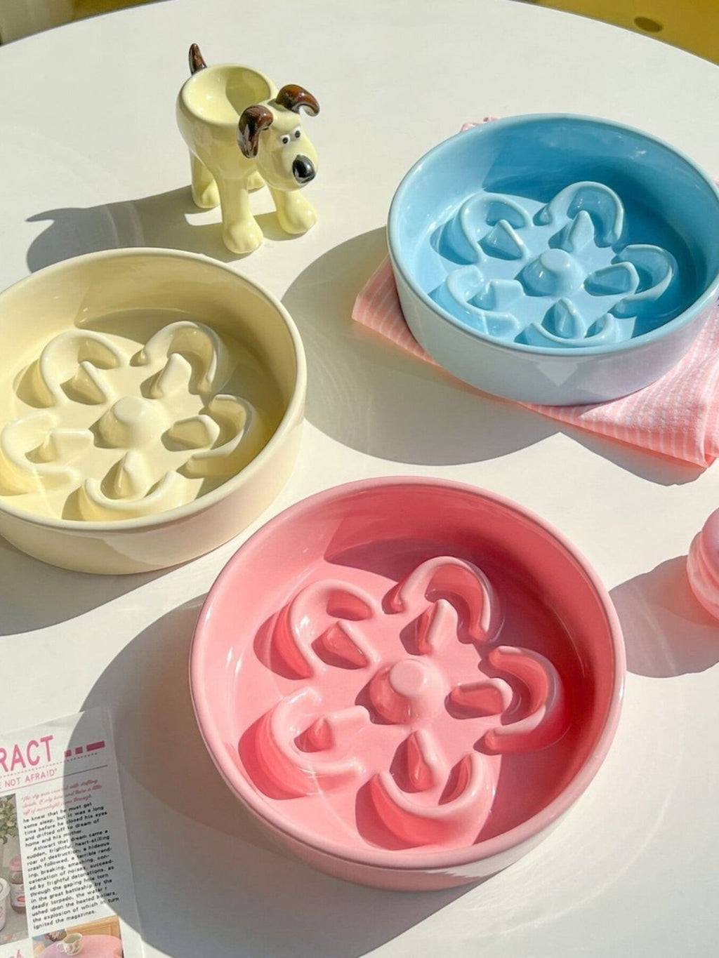 Little Pets Club pastel ceramic slow feeder pet bowls in pink, yellow, and blue, shaped like flowers to encourage slower eating for cats and small dogs.