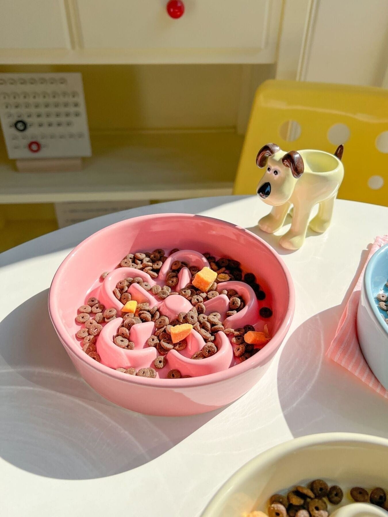 Little Pets Club pink ceramic flower slow feeder pet bowl filled with kibble and treats for cats and small dogs.