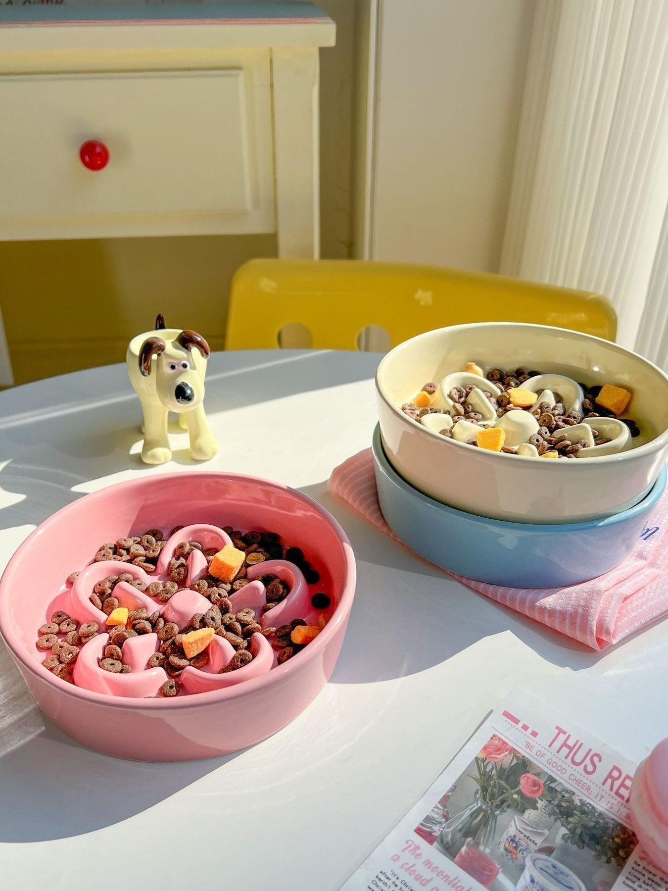 Little Pets Club pink ceramic slow feeder pet bowl with flower design filled with kibble and treats.