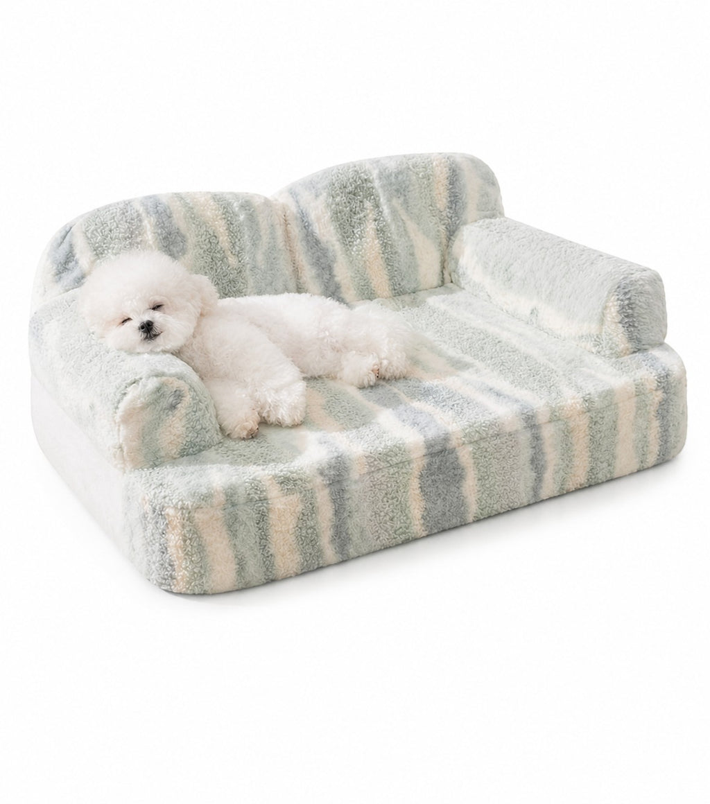 Little Pets Club plush pet sofa bed with raised bolsters and a white Bichon Frise dog resting on it. The bed has a striped pattern in blue, green, and cream.