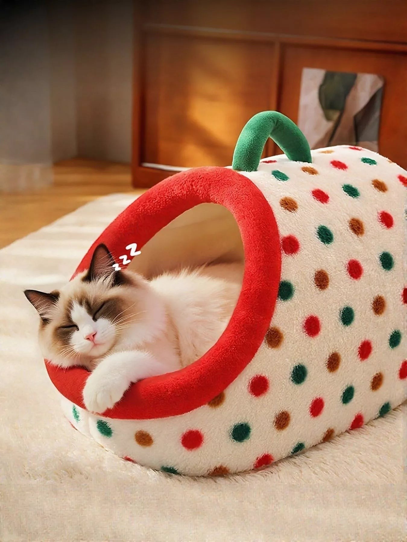 Little Pets Club plush enclosed cat bed with red trim, polka dot design, and green carry handle. A fluffy cat sleeps inside.