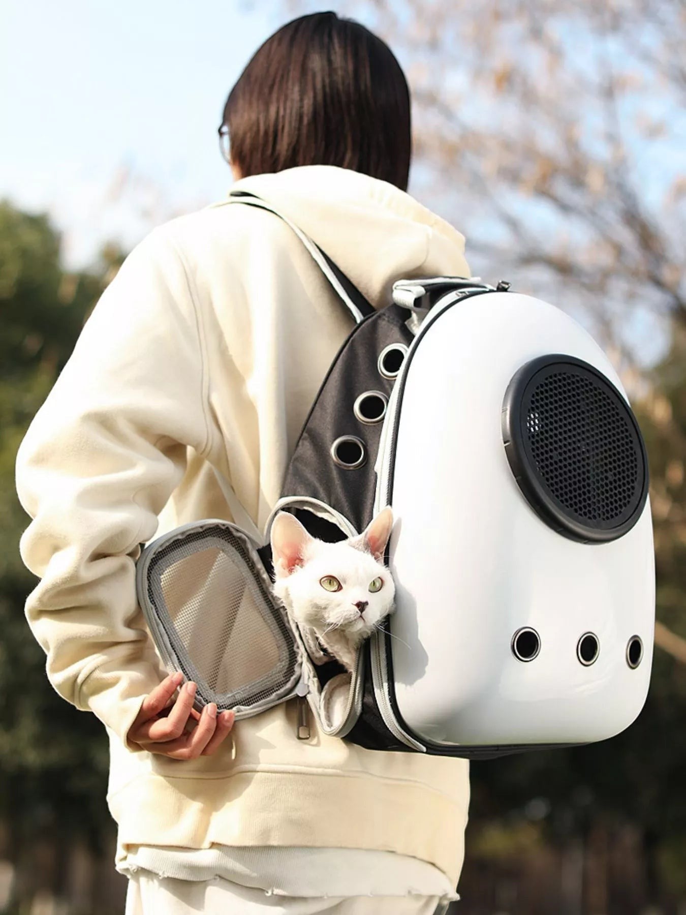 Little Pets Club white space capsule pet carrier backpack with a white cat peeking out. Features a transparent dome and ventilation holes.