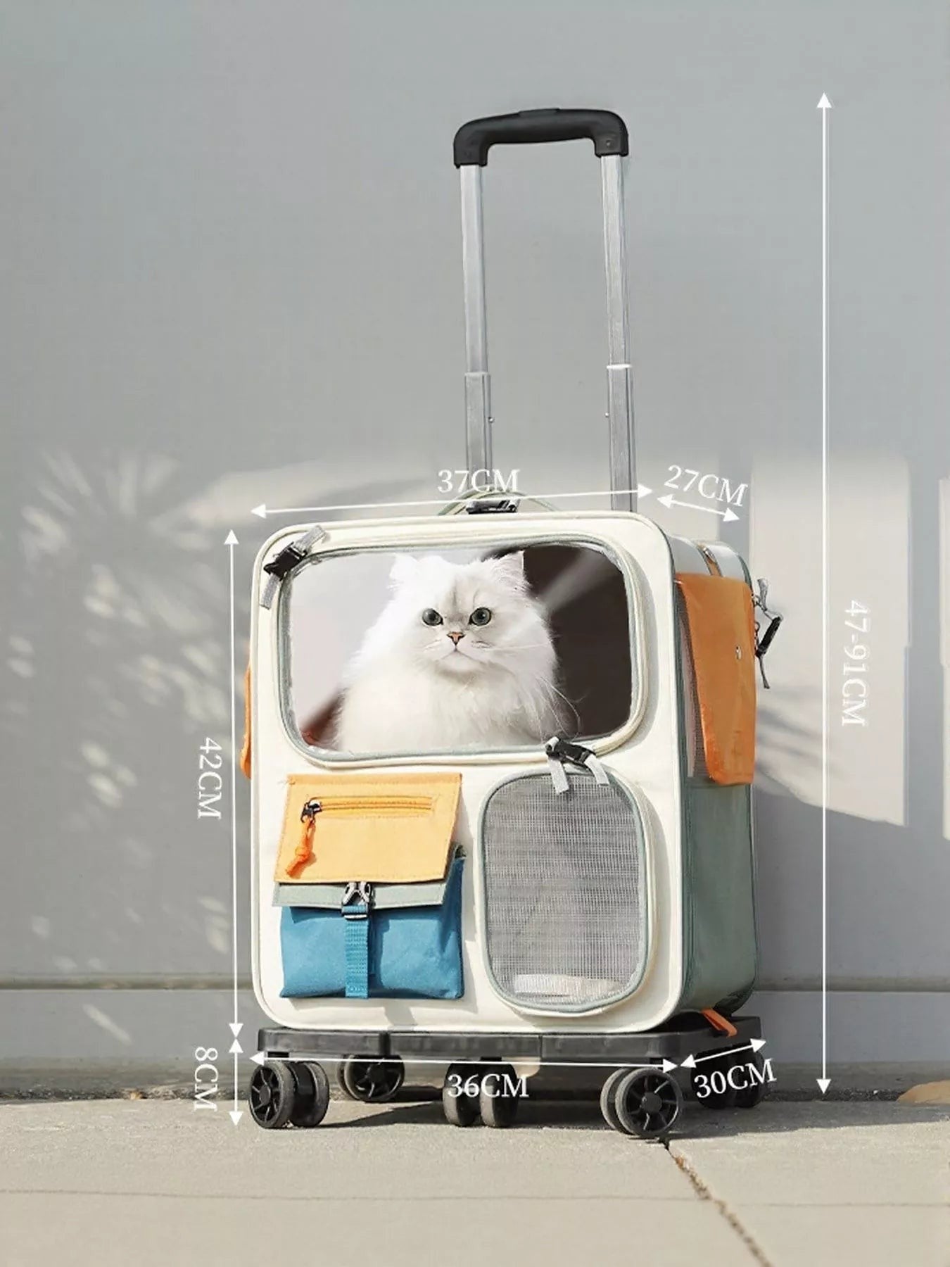 Little Pets Club wheeled pet carrier in cream and green with orange accents, featuring a clear viewing window with a white cat, multiple pockets, and rolling wheels.