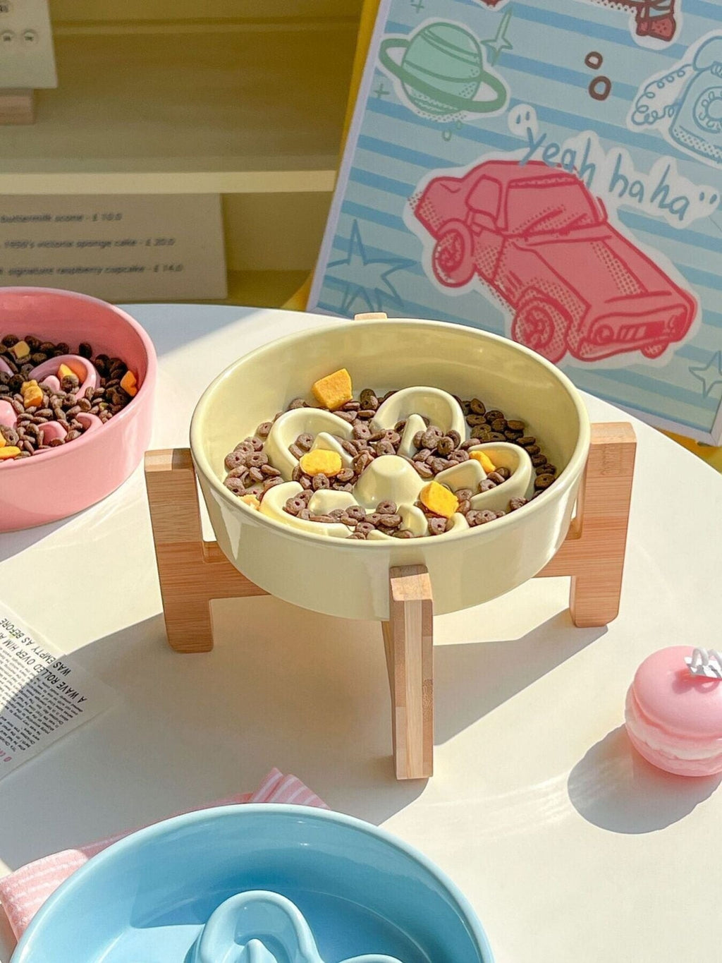 Little Pets Club pastel yellow ceramic flower slow feeder pet bowl with wooden stand, filled with kibble and treats.