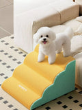 little pets club yellow 4-step foam pet stairs with a white bichon frise dog on top, next to a cream sofa.