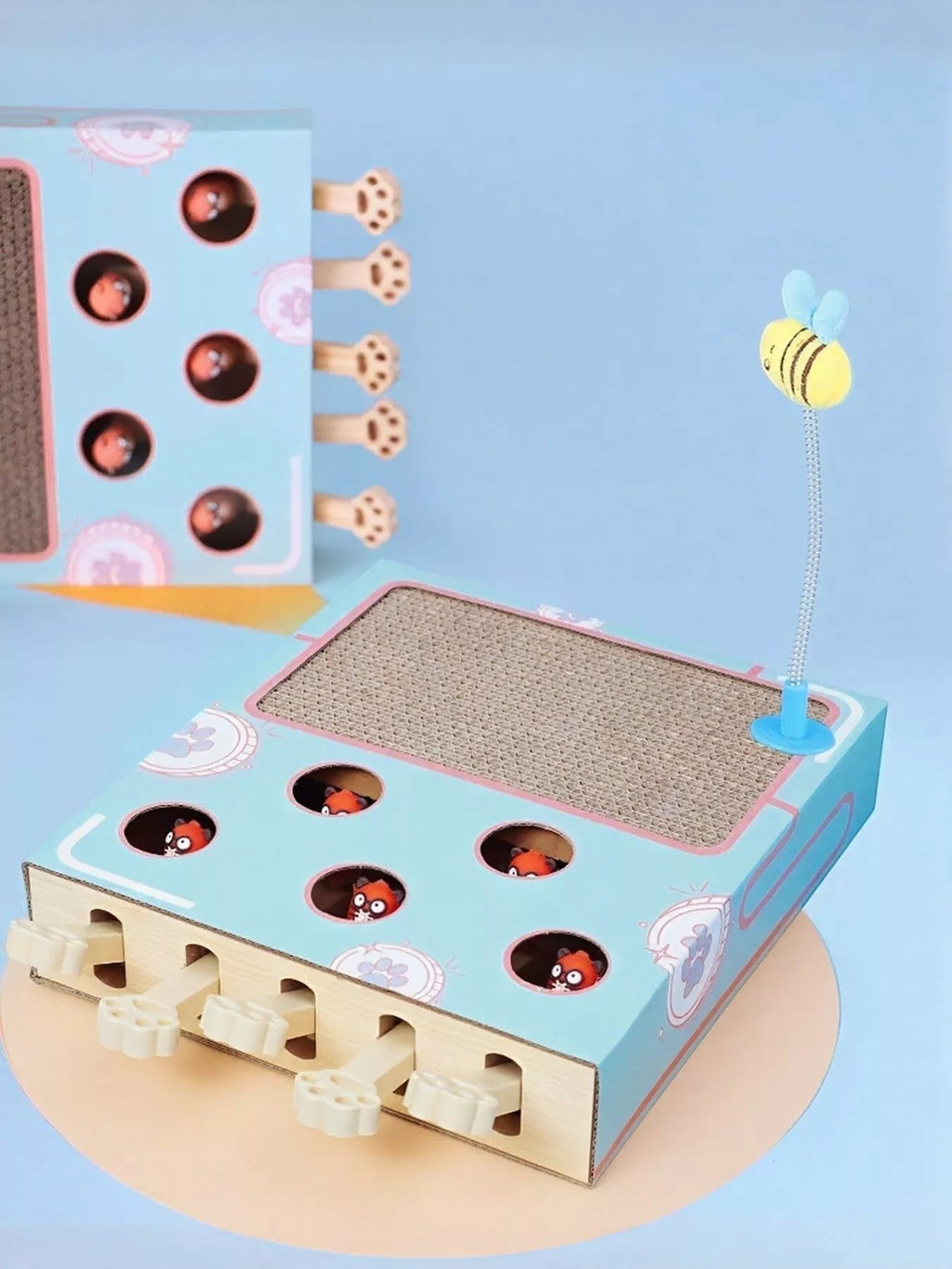 Little Pets Club interactive cat scratching box with whack-a-mole game and bee toy. Blue cardboard with corrugated scratch surface.