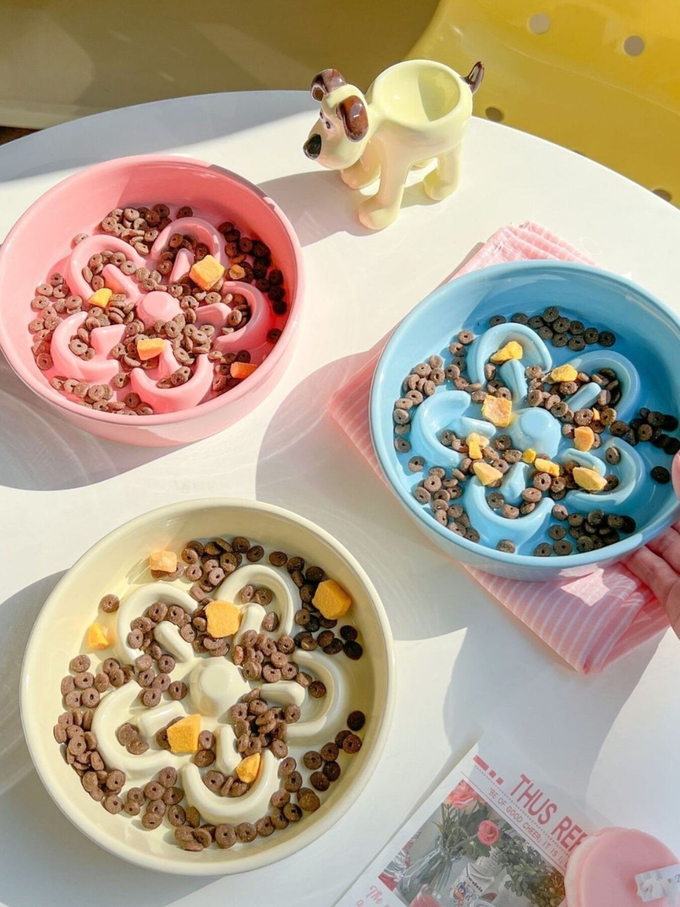 Little Pets Club pastel ceramic slow feeder pet bowls in pink, blue, and yellow, shaped like flowers to encourage slower eating.