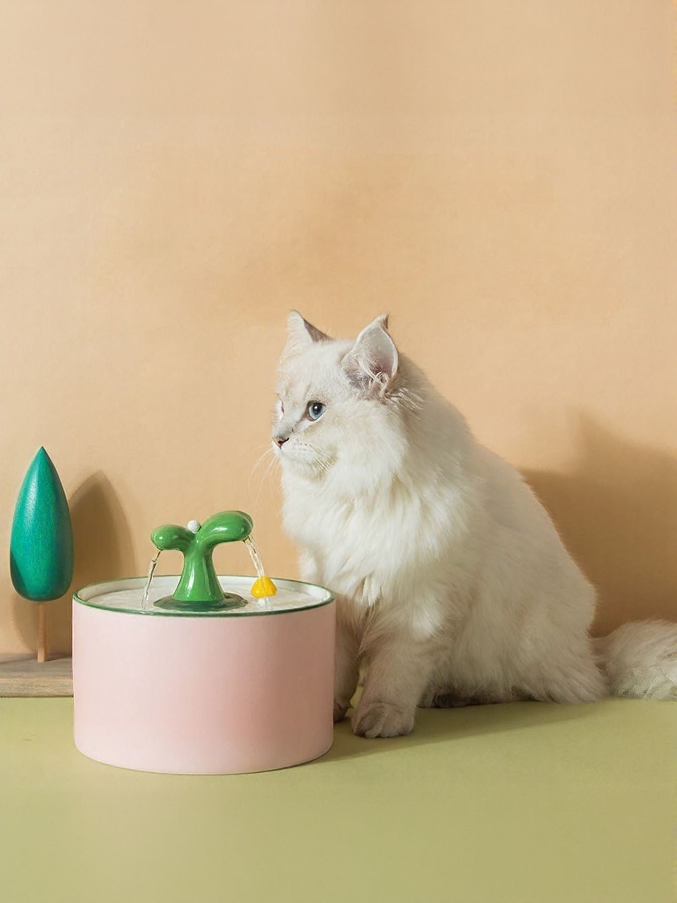 Little Pets Club pink ceramic pet water fountain with green mushroom spout, a white cat sits beside it.
